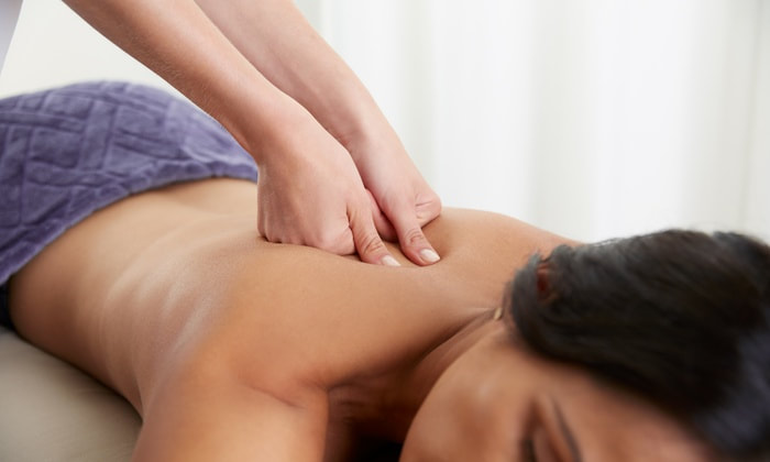 A woman getting a deep tissue massage with a blue towel over the lower half of her body.