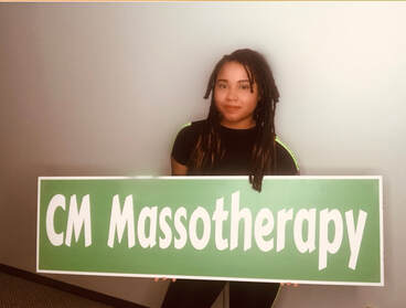 A massage therapist holding a green sign that says CM Massotherapy.