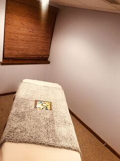 Picture taken at CM Massotherapy in Erie, Pennsylvania of one of the massage rooms.  There is a massage table in the middle of the room draped with sheets and a painting.